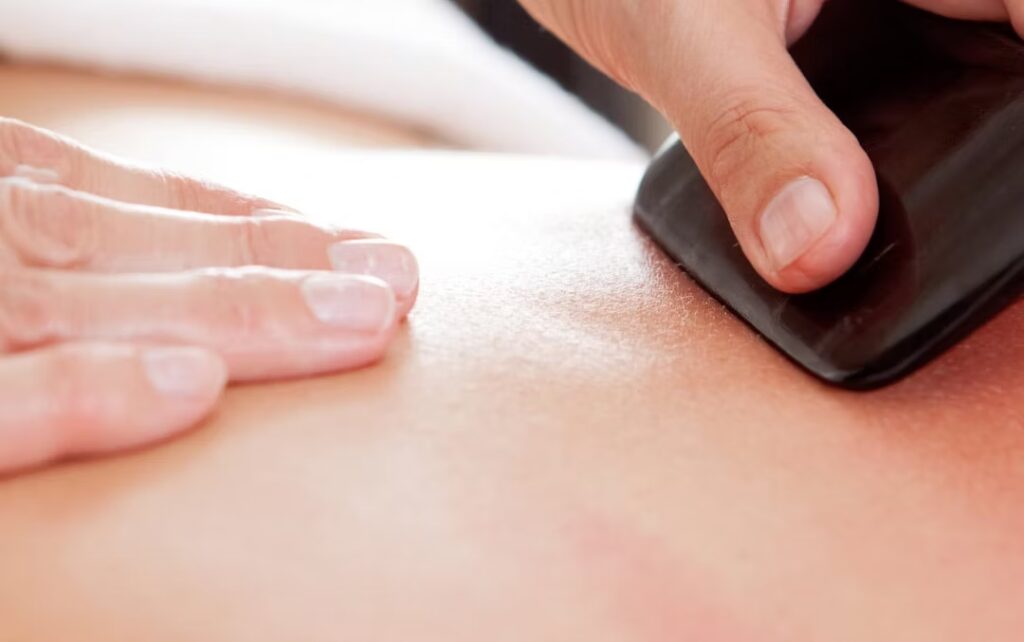 Gua Sha: pietra nera che sfrega sulla pelle oliata della schiena