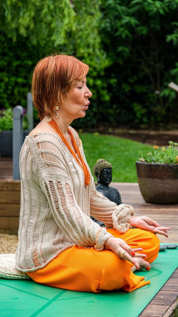 Donna che medita all aperto su un tappetino da yoga in un giardino