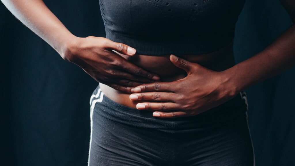 Persona che preme le mani sull addome per dolore o disagio