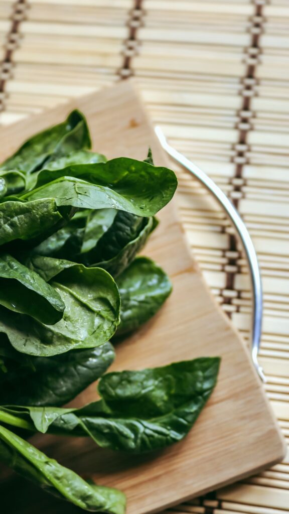 Foglie di spinaci freschi su un tagliere di legno