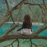 Donna che pratica meditazione in natura sopra un lago tranquillo