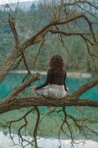 Donna che pratica meditazione in natura sopra un lago tranquillo